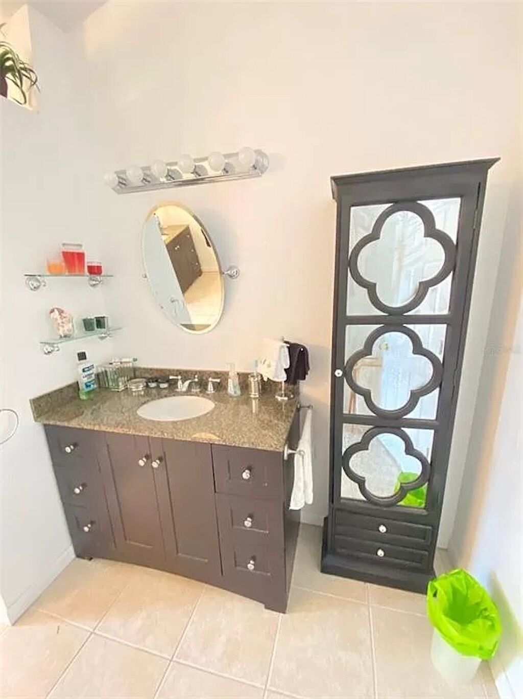 Un bany amb un lavabo de superfície de granit, un mirall gran i un moble fosc amb calaixos.
