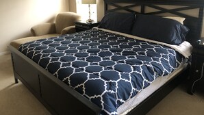 Un dormitorio con cama, una silla, una mesita de noche y una lámpara.