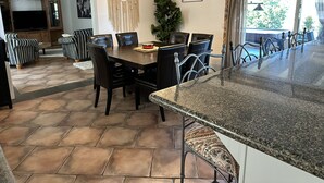 A modern kitchen with a granite countertop, a dining area with a wooden table and black chairs, and a living room with a TV and leather sofas. - 3Bd/2b home, near wedding locations, wineries, Temecula, Resort & Casinos, Views (Fallbrook)