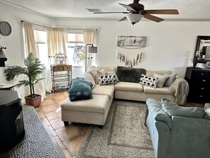 A cozy living room with a sectional sofa, a small table, a potted plant, and a fireplace.
