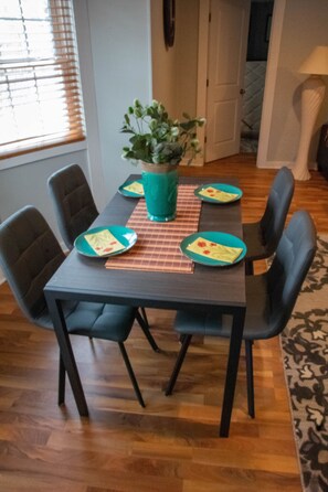 A dining table with four chairs, a potted plant, and plates with food.
