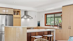 A modern kitchen with a central island, stainless steel appliances, wooden cabinetry, and a large window providing natural light.