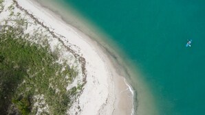 Ein Luftbild von einem Strand mit einem kleinen Boot auf dem Wasser.