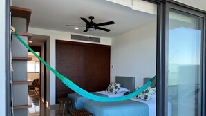 Un dormitorio moderno con cama, hamaca y ventilador de techo.