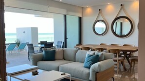 Una sala de estar moderna con sofá, mesa de centro y otoman, un comedor con mesa de madera y sillas, y un ventilador de techo.
