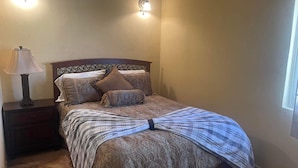 Ein Schlafzimmer mit Bett, Nachttisch, Lampe und Wandleuchten.