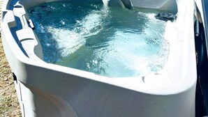 A hot tub in front of a house with a window and a door. - Studied Perfection (Spearfish)