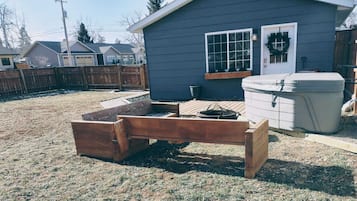 Un jardin avec un banc en bois, un petit abri de jardin et un jacuzzi.