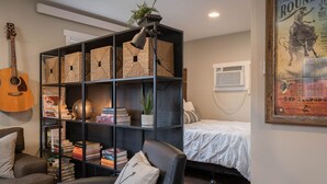 A cozy room with a bookshelf, a guitar, a bed, and a poster on the wall. - Studied Perfection (Spearfish)
