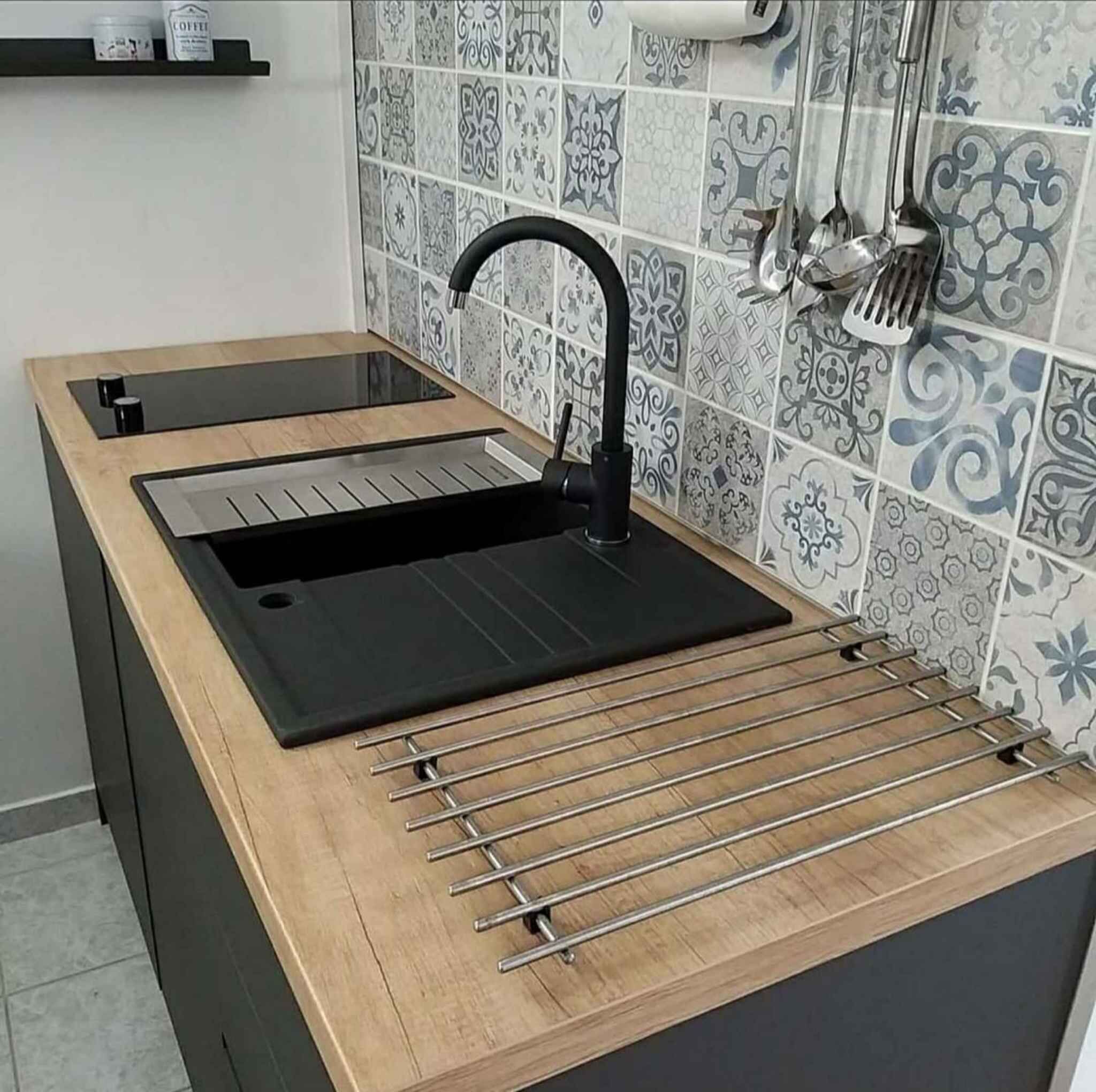 A kitchen with a black sink, a wooden countertop, and a tiled backsplash.