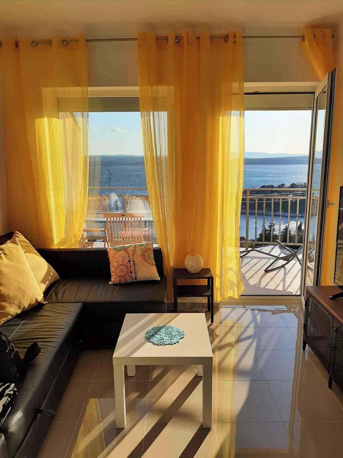A modern living room with a sofa, a coffee table, and a view of the sea.