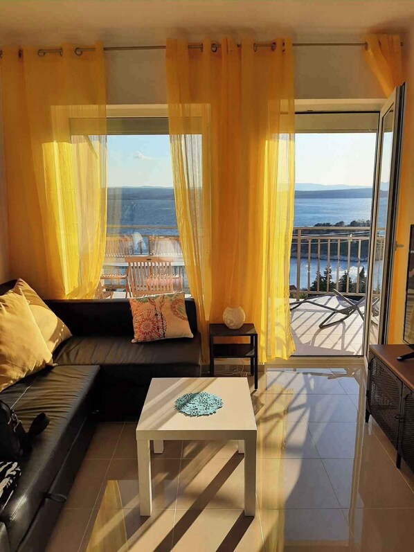 A modern living room with a sofa, a coffee table, and a view of the sea.