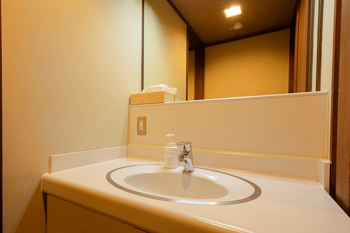 Un baño con un lavabo blanco, un espejo y una puerta con interruptor de luz.