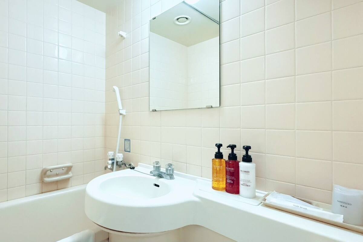 Un baño con lavabo blanco, espejo y paredes con azulejos.
