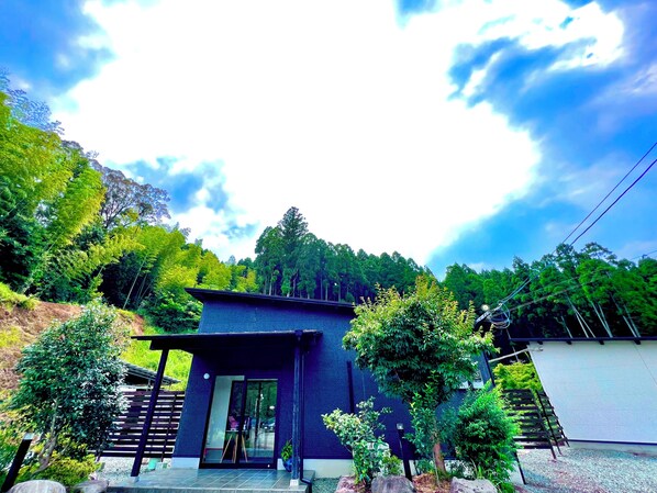 A modern house with a dark exterior, a glass door entrance, and a small porch. - Hanare Ohka (Yamaga)