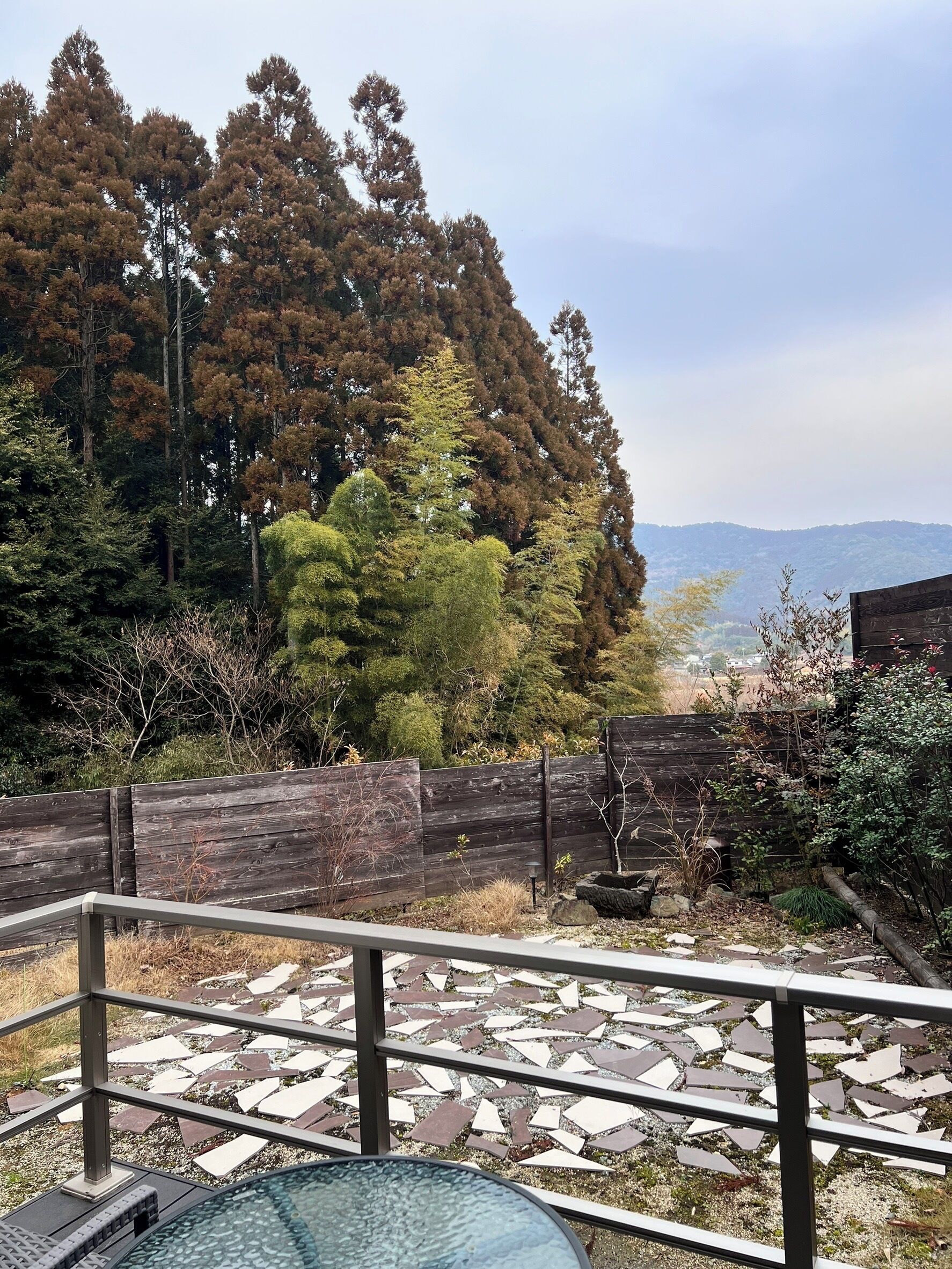 A patio area with a view of a forest and distant hills.