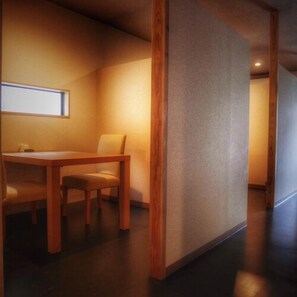 Ein Zimmer mit einem Holztisch, Stühlen, einem Fenster und einer strukturierten Wand.