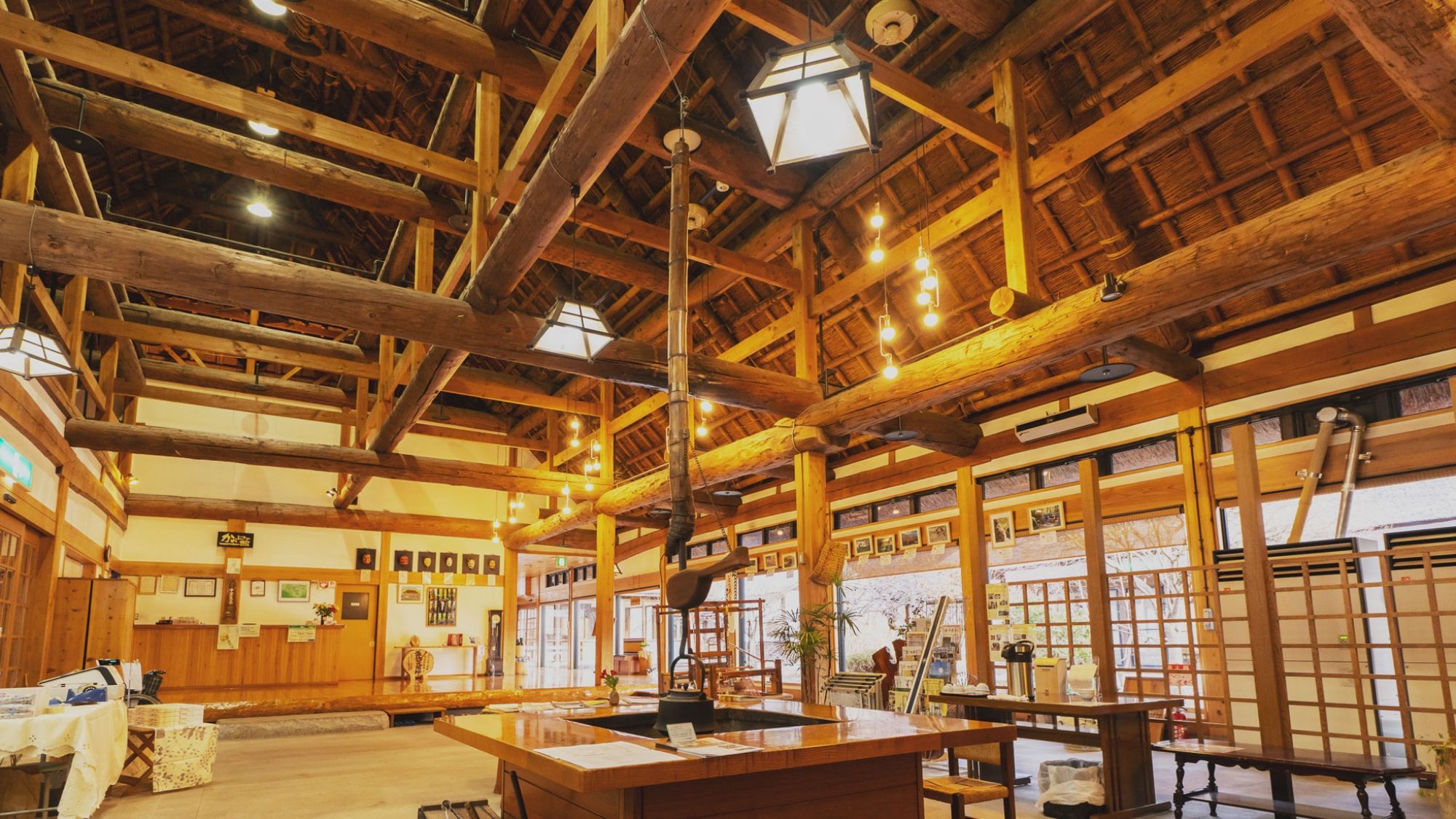 A spacious interior with high wooden beams, a central table, and a traditional Japanese aesthetic.