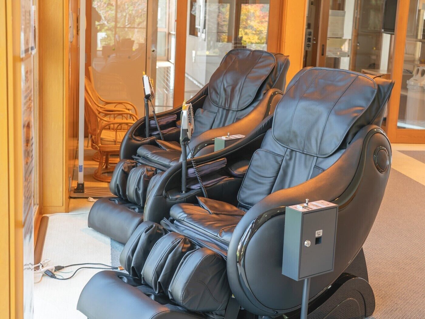 Een massagestoel met bedieningspaneel, stroomkabel en oplaadstation.
