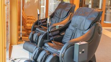 Een massagestoel met bedieningspaneel, stroomkabel en oplaadstation.