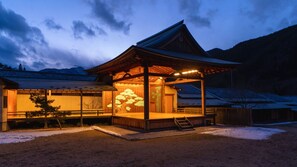 Un edificio japonés tradicional con estructura de madera, un acceso cubierto y un paisaje nevado.