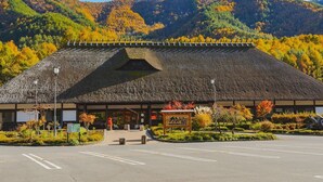 A traditional Japanese building with a sloped roof, surrounded by autumn foliage and mountains. - Green Village Yokokawa Kayabuki No Yakata (Tatsuno)