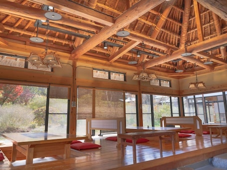 A spacious room with wooden beams and large windows offering views of the outdoors.