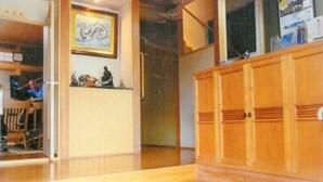 A room with a wooden cabinet, a tiled floor, and a framed artwork on the wall. - Tomiya Kinbe-tei (Ozu)