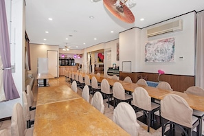 A hotel room with a long dining table, multiple chairs, a bar area, and a ceiling fan. - Tenjin Lodge (Minakami)