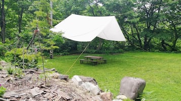 A tent set up in a grassy area with a picnic table nearby.