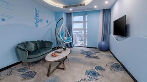 A modern room with a curved ceiling, a green sofa, a hanging chair, a flat-screen TV, and a large window. - Hairui Hotel (Chongqing)