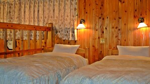 Une chambre avec deux lits en bois, une tête de lit en bois, une horloge et deux lampes fixées au mur.
