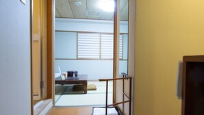 A traditional Japanese room with tatami flooring, a low wooden desk, and a sliding shoji screen door. - Hotel Fukuya (Takamatsu)