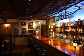 A bar area with a wooden counter, bar stools, and shelves stocked with bottles. - Hotel Fukuya (Takamatsu)