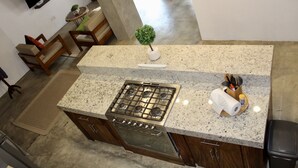 Cocina con encimera de granito, estufa de acero inoxidable y armarios de madera.