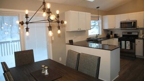 A modern kitchen with white cabinets, a central island, and a hanging light fixture.