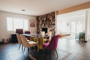 Zona pranzo con tavolo e sedie in vetro, parete in pietra e vista sull'esterno.