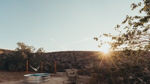 A circular pool with a hammock in a desert landscape.