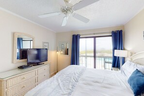 Relax in this serene hotel room with a large bed, flat-screen TV, and ceiling fan.