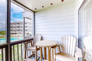 Enjoy a refreshing view of the pool from this balcony with a table and chairs.