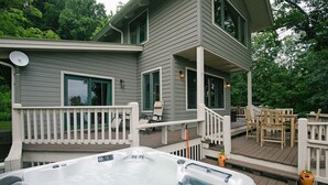 Een tweelaags huis met een jacuzzi op het terras, een overdekte patio en tuinmeubilair.