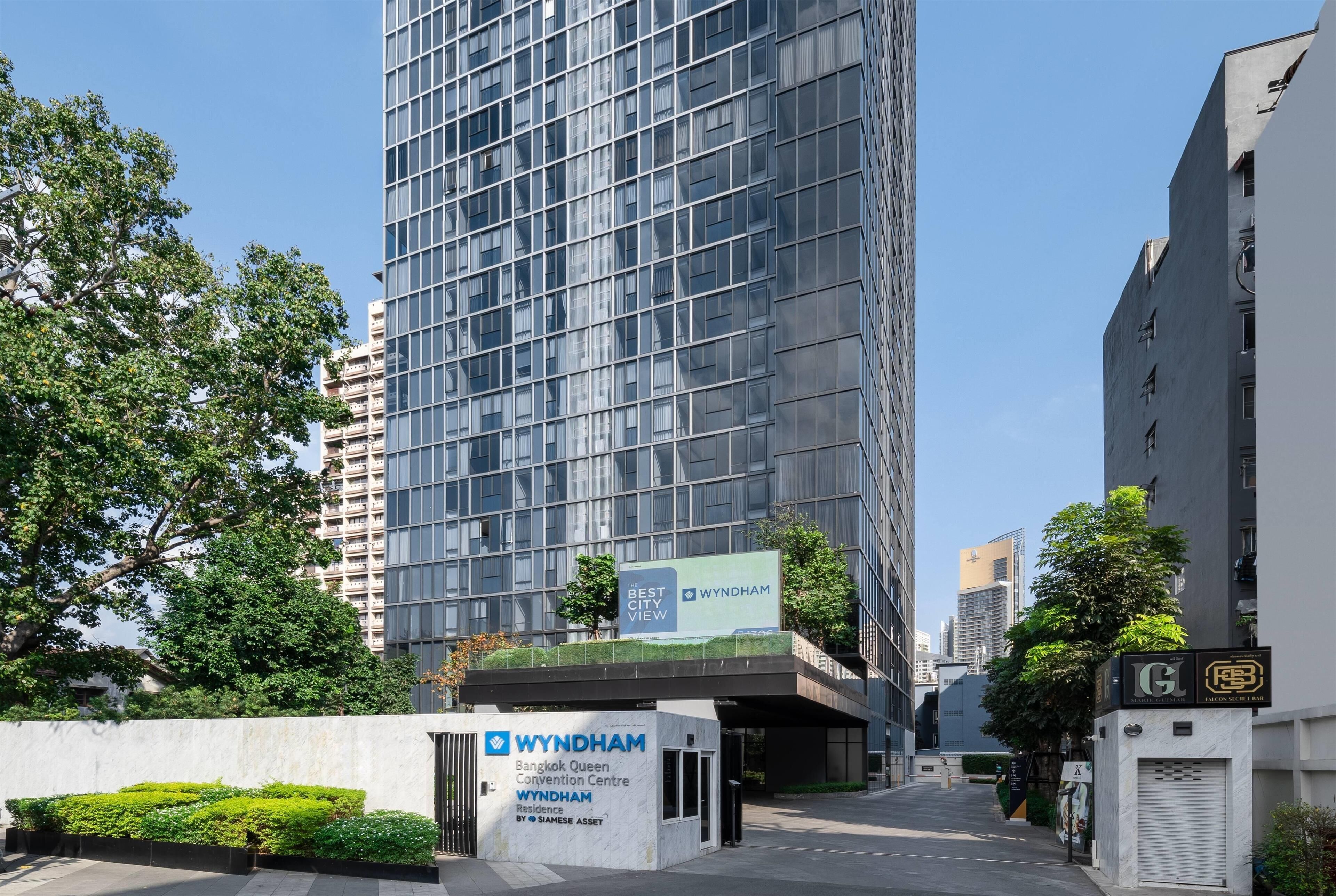 A modern building with a sign for Wyndham Bangkok Queen Convention Centre.
