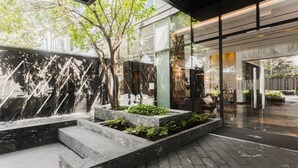Ein moderner Innenhof mit Wasserspiel, Steintreppe und Glasfassade.