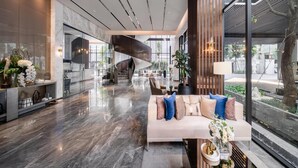 Eine moderne Lobby mit einer geschwungenen Treppe, einer Sitzecke mit einer Couch und einem Empfangstisch mit Pflanzen.
