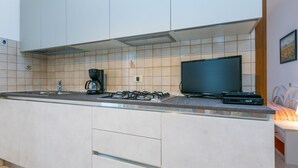 Una cocina moderna con estufa a gas, cafetera y televisión de pantalla plana.