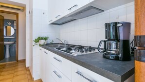Eine moderne Küche mit weißen Schränken, einem Gasherd, einer Kaffeemaschine und einem Spülbecken.