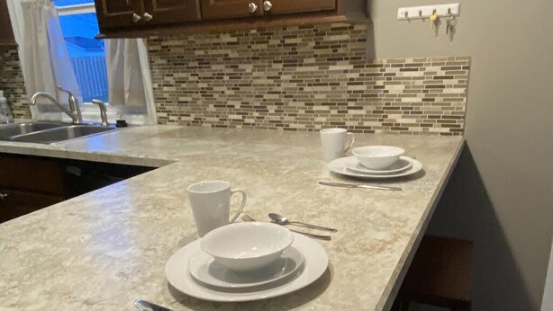 A kitchen with a marble countertop, a sink, and a window with curtains. - 3 Bedroom House in Fort Recovery (Fort Recovery)