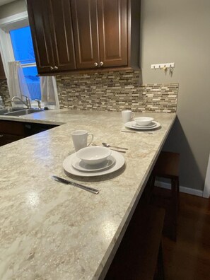 A kitchen with a marble countertop, a sink, and a window with curtains. - 3 Bedroom House in Fort Recovery (Fort Recovery)
