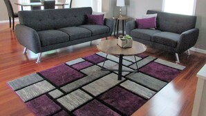 A living room with two grey sofas, a round coffee table, and a purple and grey rug. - 3 Bedroom House in Fort Recovery (Fort Recovery)