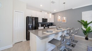 A modern kitchen with white cabinets, stainless steel appliances, and a central island with bar stools. - FA4381 Storey Lake Home 4Beds 3baths Private Pool and Free Waterpark (Kissimmee)